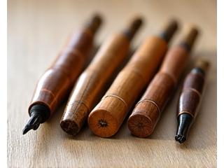 Hand-carved bamboo calligraphy pen handles displayed on a smooth wooden surface.